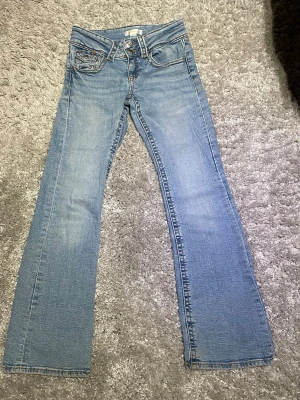 Ljusblå low waist jeans från Gina Tricot - Säljer ett par ljusblå jeans från Gina Tricot i storlek 152. Klassisk femficksmodell med raka ben och normal passform. Jeansen har snygga kontrastsömmar och är tillverkade i mjukt denimtyg som är skönt att bära hela dagen.