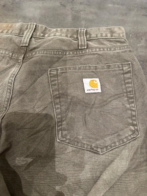 Vintage Carhartt relaxed fit 33/32 - Säljer ett par bruna Carhartt jeans i relaxed fit med klassisk femficksdesign och logga på bakfickan. Perfekta för dig som gillar en lite lösare passform och enkel, clean stil.