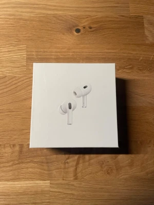 AirPods Pro - Säljer ett par Apple AirPods Pro i originalförpackning med komplett tillbehör: laddningsetui, laddningskabel, extra öronproppar och manualer. Allt ser ut att vara i mycket gott skick, perfekt för dig som vill ha trådlösa hörlurar med aktiv brusreducering och hög ljudkvalitet.