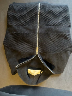 Svart stickad kofta från Selected Homme - Säljer en svart stickad kofta från Selected Homme med grov struktur och hel dragkedja framtill. Koftan har ribbade muddar och en clean, modern look som passar perfekt till lager-på-lager. Grym till både jeans och chinos.