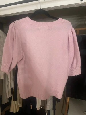 Ljusrosa stickad tröja med puffärm - Supersöt ljusrosa stickad tröja med puffiga trekvartsärmar och rund hals. Tröjan har ribbade muddar vid ärmslut och nederkant, vilket ger en snygg och bekväm passform. Perfekt för dig som vill ha en mjuk och trendig vardagströja.