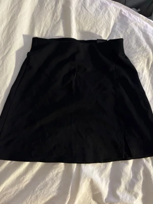 Svart mini kjol  - Enkel och stilren svart kortkjol i mjukt bomullstyg. Kjolen har en rak passform och är perfekt att matcha med en crop top eller oversized tröja. Klassisk design utan detaljer för en clean look.