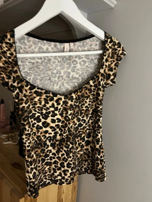 Leopardmönstrad topp från Nelly - Snygg topp från Nelly i leopardmönster med beige och svarta toner. Modellen har korta ärmar och en djup v-ringning. Tunt och mjukt material 💓💓