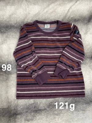 Randig långärmad tröja Polarn O. Pyret - Säljer en mjuk och skön långärmad tröja från Polarn O. Pyret i storlek 98. Tröjan har ett randigt mönster i lila, vinrött, orange, vitt och mörkblått. Perfekt för höst och vår!🌸 Fint använt skick. Storlek 98