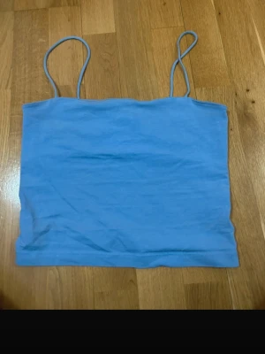 Två linne-toppar från Gina Tricot S - Säljer två stilrena linne-toppar från Gina Tricot i storlek S. En är ljusblå och den andra är rostbrun, båda med tunna axelband och rak passform. Perfekta att matcha med jeans eller kjol för en enkel och snygg look. 