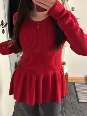 Gina Tricot - Supersnygg röd stickad tröja med ribbad struktur och volang nedtill. Långärmad modell som sitter tajt upptill och släpper ut i en fin peplumform. Perfekt för dig som vill ha en färgklick i garderoben❣️