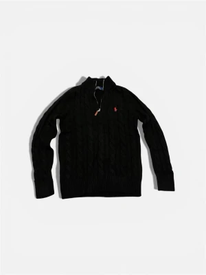 Svart stickad tröja Polo Ralph Lauren - Svart kabelstickad tröja från Polo Ralph Lauren med röd broderad logga på bröstet. Tröjan har lång ärm, ribbad krage och muddar samt en snygg half zip-dragkedja med läderdetalj. Perfekt för dig som gillar klassisk och stilren look.