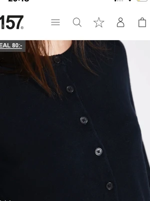 Svart cropped kofta med knappar - Stilren svart cropped kofta med rund halsringning och knäppning framtill. Långärmad modell i mjukt, tunt material som passar perfekt till jeans eller kjol. Enkel och trendig design som är lätt att matcha.