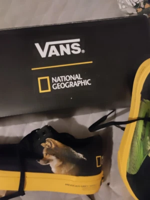 Vans x National Geographic sneakers old skool  - Helt nya icke använda Unika limited edition Vans sneakers i samarbete med National Geographic. Old skool bra skick Skorna har svart ovandel i textil med färgglada djurmotiv, gul sula och svarta snören. På sidan finns tryck av Mexican Grey Wolf och Red-Eyed Tree Frog samt National Geographic-logga Storlek finns på sista bilden. Orginalkartong medföljer. 