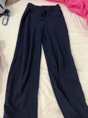 Svarta mjukisbyxor med snörning - Mysiga marinblåa low waist mjukisbyxor med dragsko i midjan och raka ben. Perfekta för chill dagar hemma eller när du vill vara extra bekväm. Tillverkade i mjukt material som känns skönt mot huden.