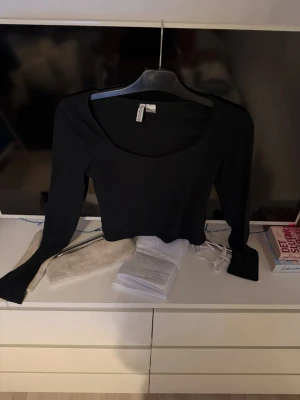 Svart crop top från H&M  - Säljer en svart långärmad crop top från H&M Divided. Tröjan har en bred, rundad urringning och är tillverkad i ett stretchigt material som sitter tajt. Perfekt att styla med höga jeans eller kjol för en trendig look. Ordpris:150kr ish säljer för 90kr plus frakt 