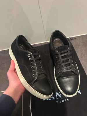 Svarta Lanvin sneakers i mocka och skinn - Säljer nu ett par riktigt schyssta lanvin skor, skorna skulle jag säga är i 9/10 skick, inga defekter. Det är nya snören på så dom ska blir extra snygga. Har dock ingen box utan bara dust bag. Skriv gärna till mig vid minsta fundering!!