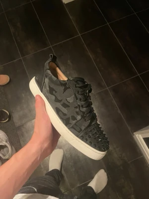 Christian Louboutin Sneakers - Tvärsköna Loubs i svart camo som faktiskt är äkta till skillnad från 90% av alla plick annonser. Storlek 40,5 passar upp till 42. Bra skick inga defekter förutom nån skråma och lite heeldrag, 8,5/10. Nypris 10.000kr+. Byten är väldigt intressant och priset är inte fast! Hör av dig för fler frågor!!! 😛😛
