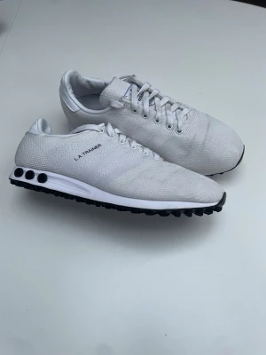 LA trainers - Nästan helt oanvända snygga vita Adidas LA Trainer sneakers med klassisk design och svarta detaljer på sulan. Storlek 44 men passar 43-43,5. Tyvärr ingen original box utan skickas i en ersättnings Nike box. Hör av er vid frågor eller funderingar!