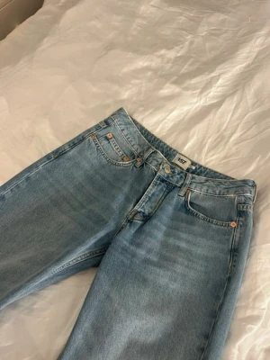 Ljusblå raka jeans, lågmidjade - Säljer ett par ljusblå jeans från 157 med klassisk femficksdesign och raka ben. Jeansen har normal midja och är tillverkade i mjukt bomullsdenim. Perfekta för en avslappnad och trendig look. Lite baggy men fint vid rumpan