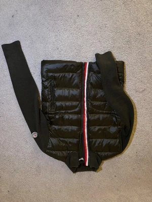 🖤 Moncler hybridjacka / stickad dunjacka - Stilren Moncler hybridjacka – perfekt mix av stickat och dun. Lätt men varm, perfekt både inne och ute. Väldigt populär modell som funkar året runt. Sportig, modern och exklusiv – exakt det Moncler är känt för.