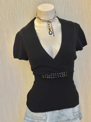 Svart stickad omlott v-ringad topp med nitar - Tag says L but it fits more like M so please check out the measurements 