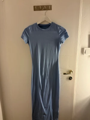 Ljusblå klänning - En enkel och stilren ljusblå långklänning med rund halsringning och korta ärmar. Aldrig kommit till användning. Storlek S. 