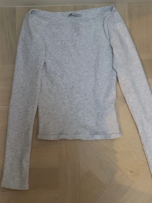 Grå långärmad boatneck tröja - Grå långärmad tröja med båturringning. Sömmen på tröjan längst ner har gått upp lite som visas på andra bilden, annars e tröjan mycket bra skick. Den är i storlek M men passar mig som oftast har xs/s.