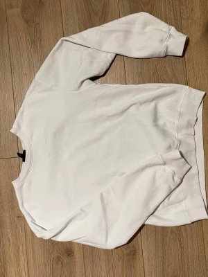 Vit loose fit sweatshirt från H&M - Säljer en vit sweatshirt från H&M i loose fit-modell. Tröjan har rund halsringning, långa ärmar och ribbade muddar vid ärmslut och nederkant. Perfekt för en avslappnad och enkel stil.