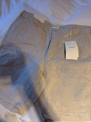 Beige linneshorts från EastWest - Snygga beige shorts från EastWest i luftigt linne. Klassisk passform med bälteshällor, gylf med dragkedja och knapp samt sidofickor. Perfekta för varma dagar och enkel att matcha med olika stilar.