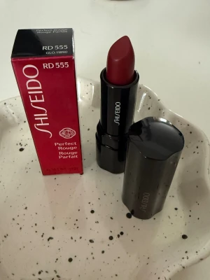Shiseido Perfect Rouge RD 555 “Spellbound” - Shiseido Perfect Rouge – RD555  (NY)  Helt nytt och oanvänt läppstift från Shiseido Serie: Perfect Rouge Nyans: Spellbound Mängd: 4 g  Endast öppnad för fotografering, aldrig testad. Originalförpackning medföljer.  Nypris ca 350–400 kr
