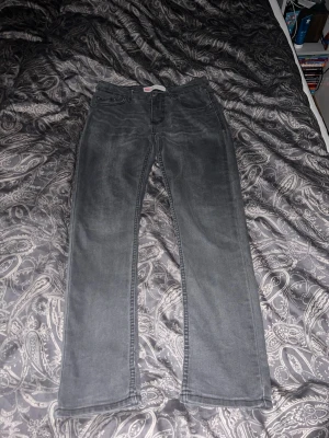 Levi's 512 Slim Taper grå jeans - Säljer ett par grå Levi's 512 Slim Taper jeans med klassisk femficksdesign och knappgylf. Jeansen har en smalare passform med avsmalnande ben och är tillverkade i mjukt jeansmaterial. Perfekta för dig som gillar en clean och stilren look.