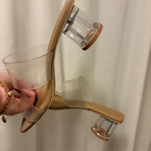 Transparenta klackskor från H&M - Säljer ett par trendiga klackskor från H&M i storlek 38. Skorna har transparenta remmar i syntet och en cool, klar cylinderformad klack. Beige innersula och fyrkantig tå ger en modern vibe. Perfekta för dig som gillar statement heels!