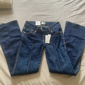 Blå bootcut jeans från 157, stl S - Snygga blå jeans från 157 med bootcut-modell och markerade pressveck framtill. Klassisk femficksdesign, kontrastsömmar och hög midja. Jeansen är i jeansmaterial och har en cool vintage vibe. Perfekta för dig som gillar en lite vidare passform nertill.