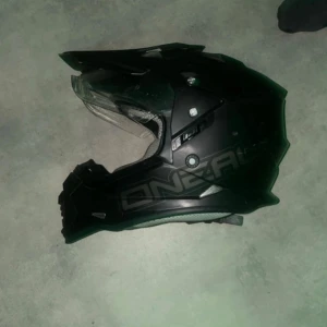 Svart O'Neal crosshjälm med visir - Säljer en svart crosshjälm från O'Neal med coolt visir och ventilerad design. Hjälmen har en sportig form, integrerat visir och vadderad insida med mesh-tyg för extra komfort. Perfekt för dig som gillar motocross eller äventyr på två hjul.