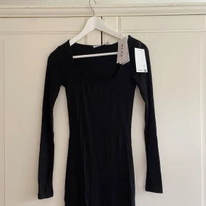 Svart ribbad klänning från NA-KD - Svart ribbad klänning från NA-KD i storlek XS. Modellen är kort med långärmade ärmar. Materialet är mjukt och stretchigt, vilket gör att klänningen sitter slim och markerar figuren. Jätteskön! Helt oanvänd, med lappar kvar! 