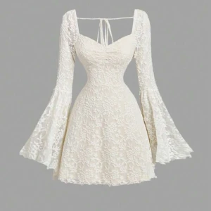 Studentklänning, Vit spetsklänning med utsvängda ärmar - Superfin vit kortklänning i spets med utsvängda långa ärmar och snygg snörning i ryggen. Klänningen har figurnära passform upptill och markerad midja, samt romantiskt blommönster i spetsen. Perfekt för dig som vill sticka ut med en unik look!