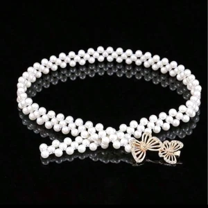 Pärlbälte med fjärilsspänne - Säljer ett elegant pärlbälte med vita pärlor och ett snyggt guldfärgat fjärilsspänne. Bältet har en smal och feminin design som ger en lyxig känsla. Perfekt för att lyfta din outfit med en unik detalj. Passar dig som gillar accessoarer med lite extra bling.