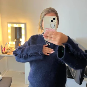 Stickad tröja med volanger - Mysig mörkblå stickad tröja från Arket med volanger längs ärmarna. Tröjan har rund halsringning och lång ärm. Aldrig använd!