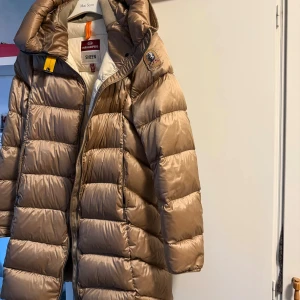 Beige dunjacka Parajumpers med huva - Nu är det dags för mig och sälja min beige dunjacka från Parajumper. Jag köpte den på Urban Modern år 2022 för 6000 kr. Den är använd vinter 2022 och 2023, knappast 2024 och ingenting 2025. Den är i väldigt bra skick, jag kommer att tvätta den innan jag skickar iväg den. Ifall du vill ha fler bilder på den så är det bara att säga till! 