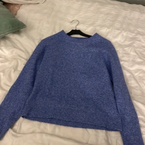 Blå stickad tröja från Vero Moda - Mysig blå stickad tröja från Vero Moda i storlek XS. Tröjan har en enkel och stilren design med rund halsringning och långa ärmar. Perfekt för lager-på-lager under kyliga dagar. Säljer eftersom den inte kommer till någon användning.
