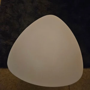 Fin bord helt nytt Perfekt till alla  - Bilderna visar ett litet bord med vit, triangulär bordsskiva och tre ben i trä. Bordet har en modern design och ser ut att vara i gott skick utan synliga repor eller skador. Perfekt som sidobord eller nattduksbord. Inga elektronikfunktioner syns.