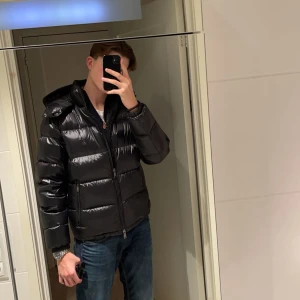 Svart pufferjacka Polo Ralph Lauren - Säljer en svart pufferjacka från Polo Ralph Lauren med glansig finish och huva. Perfekt för kalla dagar och riktigt snygg till jeans. Nypris runt 6500, säljer då den e för liten!