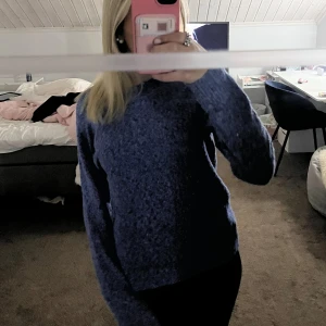 Blå stickad tröja från Vero Moda - Mysig blå stickad tröja från Vero Moda i storlek S. Tröjan har en enkel och klassisk design med rund halsringning och långa ärmar. Perfekt för kyliga dagar och enkel att matcha med jeans eller kjol.
