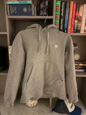 Acne Studios hoodie - En lite schysstare Acne Studios hoodie med deras facepatch på bröstet. Den är välanvänd, något urtvättad och trasig vid fickan samt ärmarna. Se bilder. Trots detta en väldigt trevlig hoodie!