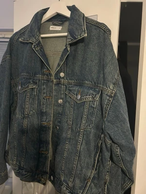 Oversized jeansjacka från Gina tricot  - Säljer en klassisk blå jeansjacka från Gina Tricot  med oversized passform. Jackan har två bröstfickor med knappar, framfickor och knappar längs hela framsidan. Perfekt att slänga över en hoodie eller t-shirt för en chill look.