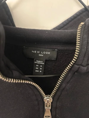 Svart half zip sweatshirt New Look - Svart sweatshirt från New Look med halv dragkedja och hög krage. Tröjan har en enkel och stilren design med ribbade muddar vid ärmslut och nederkant. Perfekt för en chill och avslappnad look.