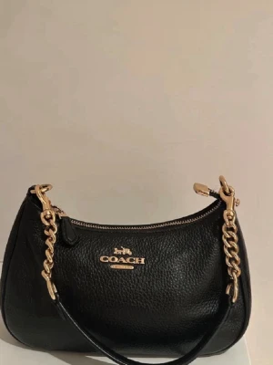 Coach handväska  - Svart väska i läder från märket coach  Köpt på Vinted så kan ej garantera autenticitet.  Säljer den då jag fick den i present men har en likadan.  Axelband, autenticitet kort och dustbag ingår.  Har dock en identisk väska jag köpt från coach och kan ej se någon skillnad mellan de.               Pris går att diskutera vid snabb affär 