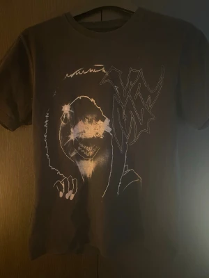 Svart t-shirt innocence v2 - Svart t-shirt från YS i bomull med ett stort grafiskt tryck framtill som föreställer en tecknad figur med huva och ett coolt, abstrakt mönster. Baksidan har stora bokstäver i vitt. Klassisk passform och rund hals. Drain gang
