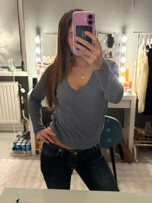 Grå v-ringad tröja från Å - Mysig grå v-ringad tröja från Å i storlek S. Tröjan har lång ärm, ribbade muddar och en klassisk passform som funkar till allt. Snygg och enkel ❣️