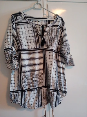 Blus svart/vit randig rutig stl 42/44 - Fin damblus med snörning i halsen och öarna går även att hängas upp med en knapp . Svart/vit randig rutig stl 42/44