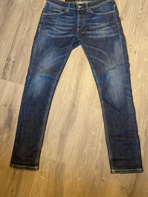 Blåa dundup George  - Säljer ett par klassiska blå jeans från Dundup i storlek 33. De har en rak passform med snygga slitningar och kontrastsömmar. Bakfickorna har den ikoniska Dondup märket och är ett perfekt par byxor för att lyxa till det