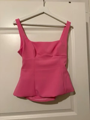 Trendig rosa topp med rosett - En jättesöt rosa topp med lite öppen rygg med rosett. En trendig tröja som inte finns att köpa längre och bara använd en gång för de tyvärr inte passar så bra på mig. Priset kan diskuteras 