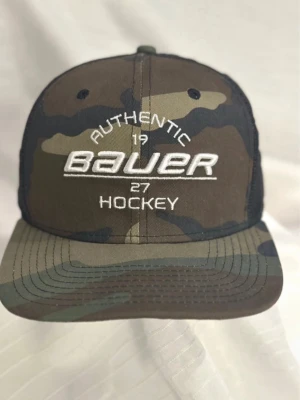 Camouflage Bauer keps från New Era - Säljer en snygg camouflagefärgad Bauer keps från New Era 9Fifty-serien. Framsidan har broderad Bauer-logga och text, medan baksidan är i svart mesh med justerbar snapback. Materialet är bomull framtill och polyester bak.
