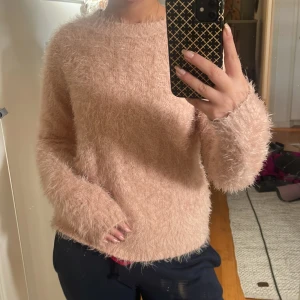 Ljusrosa fluffig stickad tröja - Supermjuk och fluffig ljusrosa stickad tröja med rund hals och långa ärmar. Perfekt för dig som vill ha en cozy och trendig look. Tröjan har en lös passform och är riktigt skön att bära under kyliga dagar.
